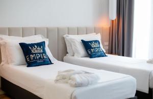 two beds with blue and white pillows in a room at Empire Beach Resort ADULTS ONLY in Dhërmi