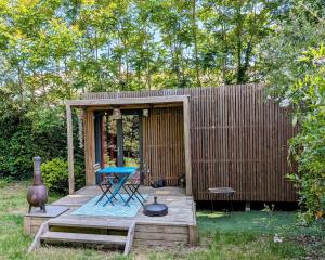 eine kleine Hütte mit einem Tisch und einem Stuhl auf einer Terrasse in der Unterkunft Studio en bois, confort et modernité in Saint-Brevin-les-Pins