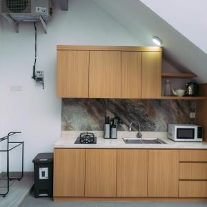 a kitchen with wooden cabinets and a microwave at The Lavana Nakula Villa Kuta Sunset in Kuta
