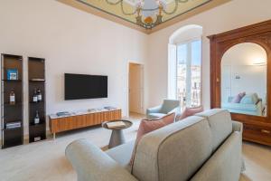 a living room with a couch and a tv at Palazzo Pupillo fine apartments by Dimore in Sicily in Siracusa
