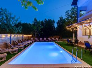 a swimming pool in a backyard with chairs and a table at Apartments Villa Mavi in Plitvička Jezera