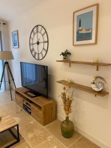 un soggiorno con TV e orologio sul muro di Maison moderne plain-pied 3 chambres jardin préau a La Rochelle