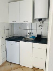 a kitchen with white cabinets and a sink at Apartments Vozab in Pag +29 photos