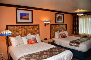 two beds in a hotel room with orange walls at Mountain View Lodge in Parowan