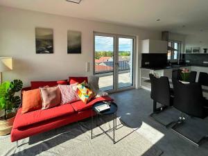 a living room with a red couch and a kitchen at Hotel und Ferienwohnungen Nebauer in Frontenhausen