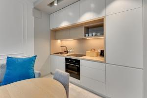 a kitchen with white cabinets and a table and a blue pillow at Tre Mare Apartments by the sea by Grand Apartments in Gdańsk