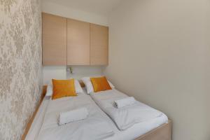 a bedroom with a bed with white sheets and orange pillows at Tre Mare Apartments by the sea by Grand Apartments in Gdańsk