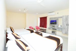 a hotel room with three beds and a tv at Royal Dreams Beach View in Pondicherry