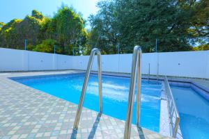 a swimming pool with two metal rails next to a fence at Royal Dreams Beach View in Pondicherry