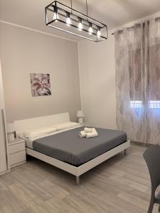 Habitación blanca con cama y lámpara de araña. en Valentina Apartments Trapani, en Trapani