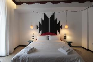 a bedroom with a large white bed with a black headboard at Bazaar Hotel in Tirana