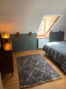 a bedroom with a bed and a rug and a window at Charmante petite maison avec baignoire Balneo et video projecteur in Chaudes-Aigues