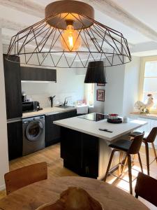 a kitchen with a large chandelier above a kitchen counter at Charmante petite maison avec baignoire Balneo et video projecteur in Chaudes-Aigues