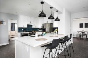 a kitchen with white cabinets and a island with bar stools at Cambridge by Porter Modern Home wHeated Pool Near El Dorado Park in Scottsdale in Scottsdale