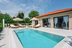 a swimming pool with chairs and umbrellas next to a house at NEW!!! Maison Mandri with Private Pool in Marasi