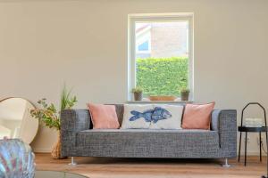 ブレスケンスにあるHello Zeeland - Vakantiehuis Zwin 112のリビングルームのソファとピンクの枕