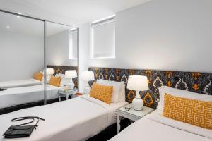 1 dormitorio con 2 camas y 2 mesas con lámparas en Oaks Melbourne South Yarra Suites, en Melbourne