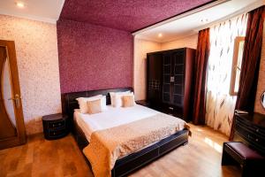 Un dormitorio con una cama y una pared morada. en Panorama Villa Lux Hotel, en Baku 113 fotos más