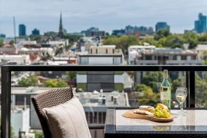 uma mesa com um prato de comida e um copo de vinho em Oaks Melbourne South Yarra Suites em Melbourne
