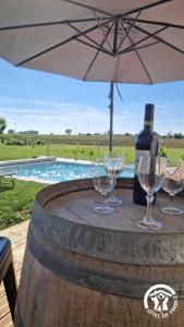 a table with wine glasses and an umbrella next to a pool at La maison de prat coutel in Labastide-de-Lévis
