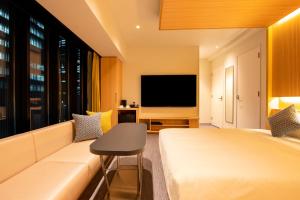 a hotel room with a couch and a television at karaksa hotel colors Tokyo Yaesu in Tokyo