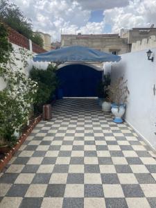 a garage with a blue umbrella on a checkered floor at Maison El Omrane 2 in Bin Rhilouf
