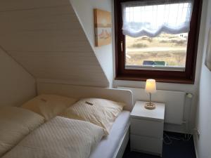 a small bedroom with a bed and a window at Zur Mühle Munkmarsch in Sylt