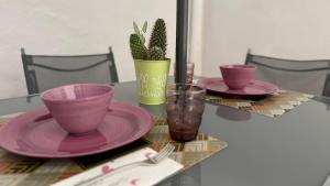 Una mesa con dos platos rosas y una planta encima. en Mazara Relax Holiday Home, en Mazara del Vallo
