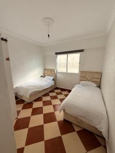 Duas camas num quarto com piso em xadrez em Tetouan Relax Apartement em Tetouan