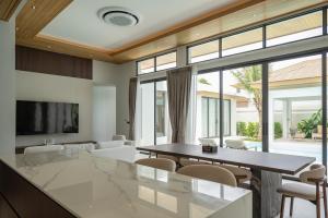 a living room with a table and chairs and a tv at Mouana Breeze Mai Khao 4-bedroom Pool Villa 9921 in Mai Khao Beach