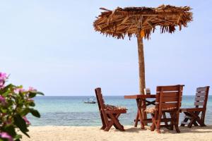 a table and chairs on the beach with an umbrella at Bottle Beach 2 Bungalows in Bottle Beach