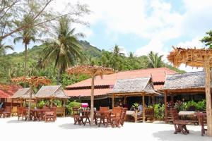 a group of tables and chairs in front of a building at Bottle Beach 2 Bungalows in Bottle Beach