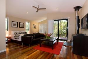 ein Wohnzimmer mit einem Bett und einem Sofa in der Unterkunft Amore On Buderim Rainforest Cabins in Buderim