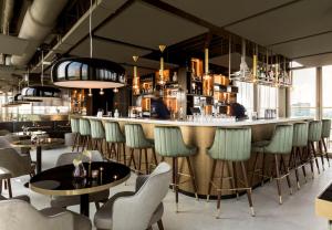 a bar in a restaurant with chairs and tables at NH Collection Eindhoven Centre in Eindhoven