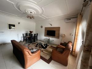 a living room with two couches and a flat screen tv at Appartement Jardin Dachille - Résidence Shalom Bonamoussadi avec Wifi, Clim, Parking, Gardien 24h in Douala