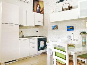 a kitchen with white cabinets and a table with chairs at A casa dei nonni in San Felice a Cancello