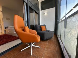 ein orangefarbener Stuhl und eine Couch in einem Zimmer in der Unterkunft Magnificent Studio Isla Cristina in Isla Cristina