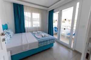 a bedroom with a bed with blue curtains and a balcony at AViSOS HOTEL & APARTMENTS in Marmaris