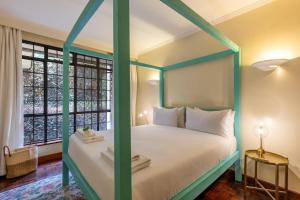 a bedroom with a green canopy bed with a window at Riverside Park Tropical Oasis 3B YourHost Nairobi in Nairobi