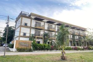 a large building with a palm tree in front of it at Casa Idaman Motel Langkawi in Pantai Cenang