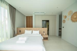 a bedroom with a large bed with white sheets at Mouana Breeze Mai Khao 4-bedroom Pool Villa 9921 in Mai Khao Beach +60 photos