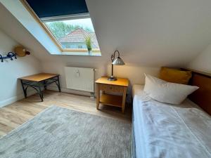 Un dormitorio con una cama y una ventana y una mesa. en Oewern Diek App 08, en Wustrow