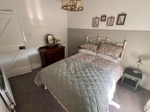 a bedroom with a bed and a table and a clock at Fiddlers Cottage in Springmount