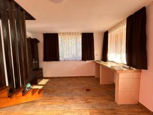 a living room with two windows and a wooden floor at Casa Mihai in Bîsca Rozilei