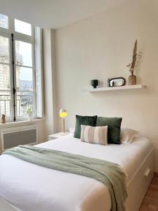 a bedroom with a large white bed with green and white pillows at Le Fablet, Hyper centre de Rennes in Rennes