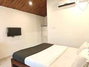 une chambre avec un lit et une télévision au mur dans l'établissement Seven Petals Cottages, à Morjim