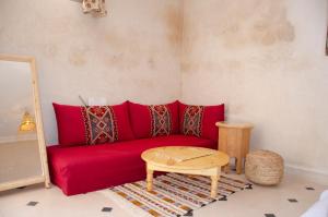 a red couch in a living room with a table at SurfAppart Morocco in Tamraght Ouzdar