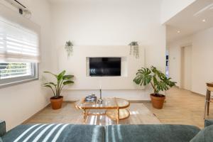 a living room with a table and potted plants at Stylish 3BR Apt w Balcony 5 min Walk from Beach with Shelter by Sea N' Rent in Tel Aviv