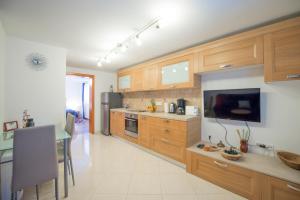 a kitchen with wooden cabinets and a table and a television at Apartments Portun in Vrsar