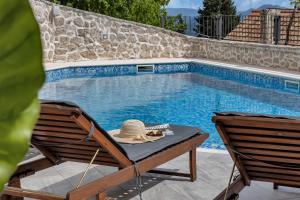 a hat sitting on a chair next to a swimming pool at Holiday Home Sonja - Makarska Exklusiv in Vrgorac